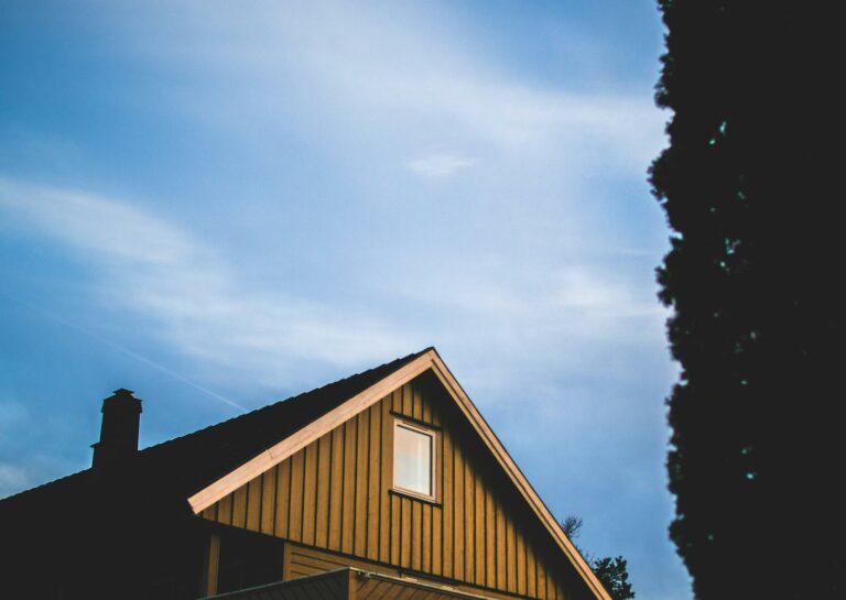 A charming rustic wooden house under a vivid blue sky with sparse clouds.